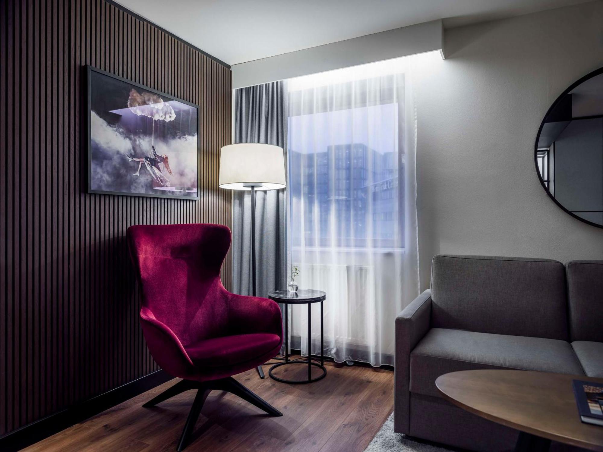 Radisson Blu Royal Viking Hotel, Stoccolma Esterno foto The photo shows a cozy and modern living area. On the left, there's a striking purple armchair with a unique design, accompanied by a round side table. Next to the chair, a floor lamp provides soft lighting. To the right, there's a gray sofa, creatin